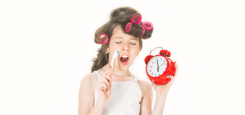 preteen with toothbrush curlers and alarm clock