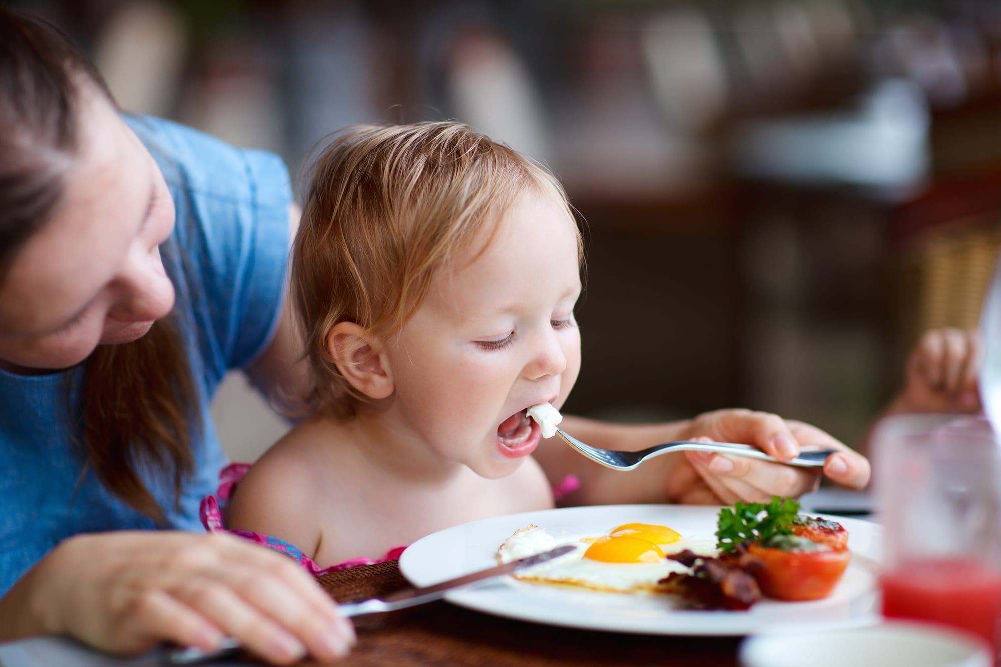 mom feeding eggs to toddler