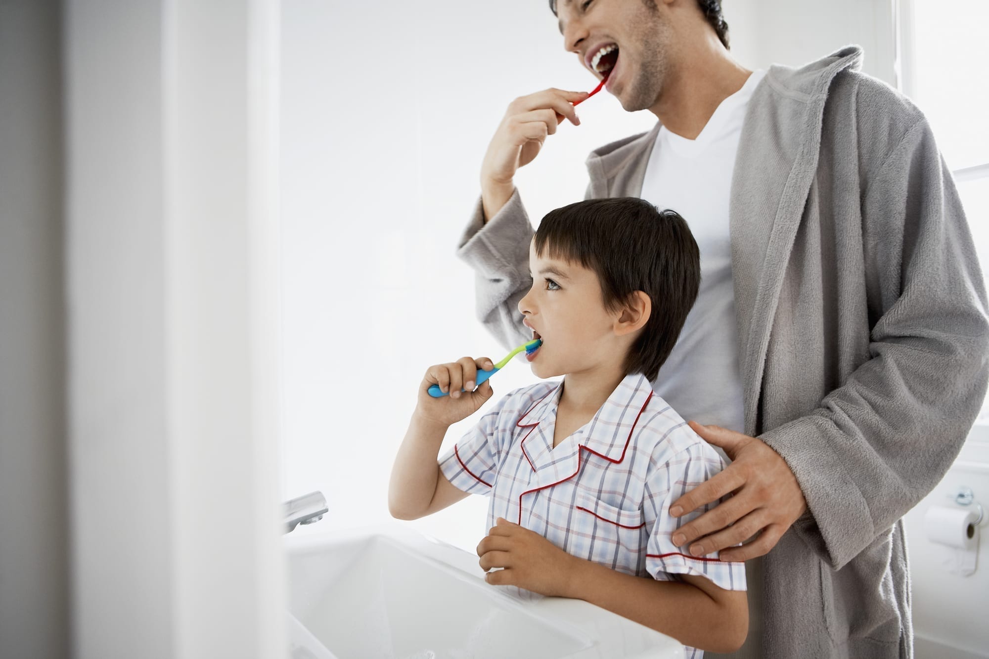 father and son brushing teeth