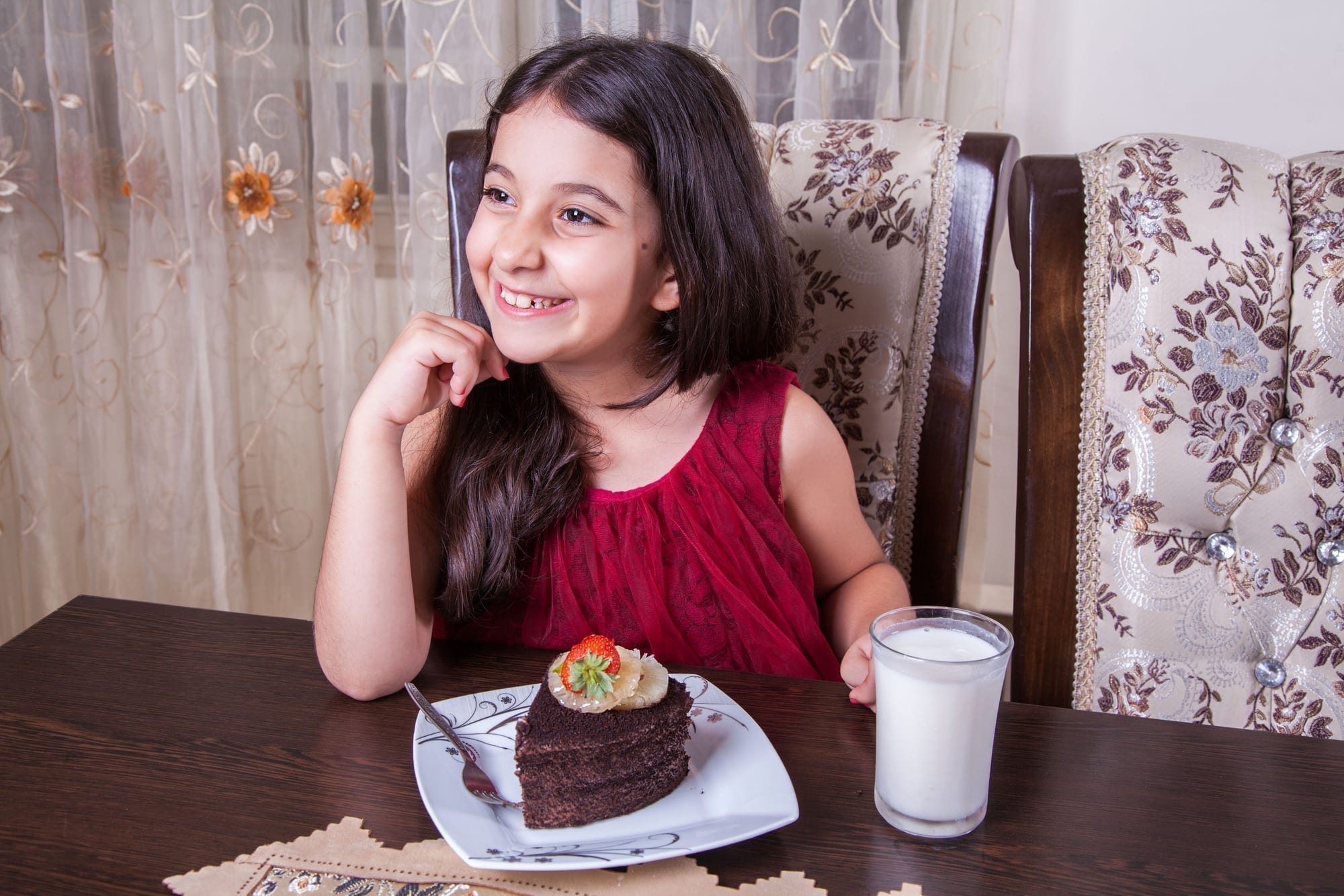 Happy girl sitting at the table and eating a cake Vector Image