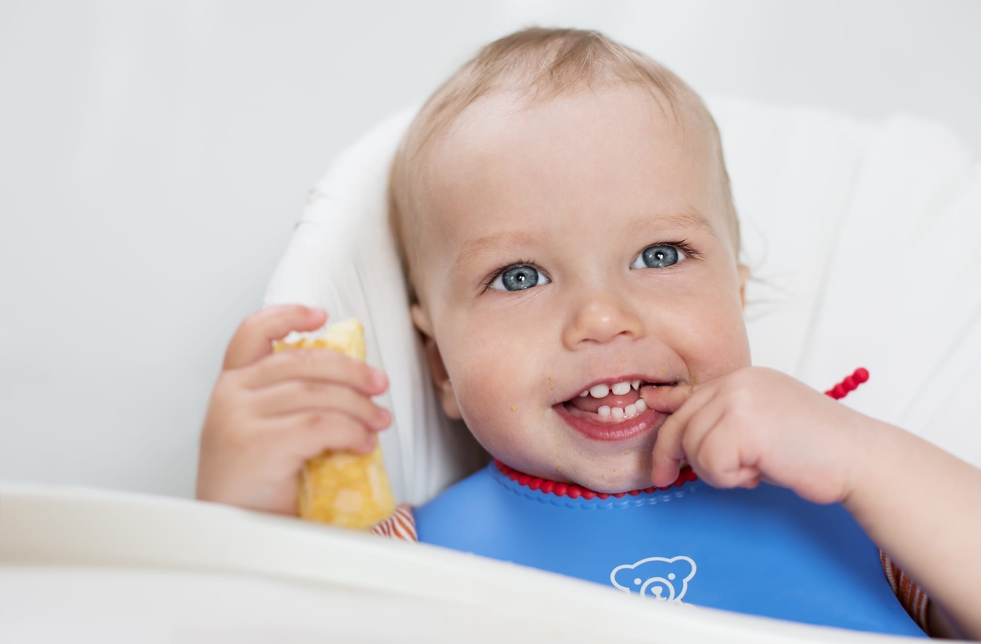 baby boy with blue eyes eating