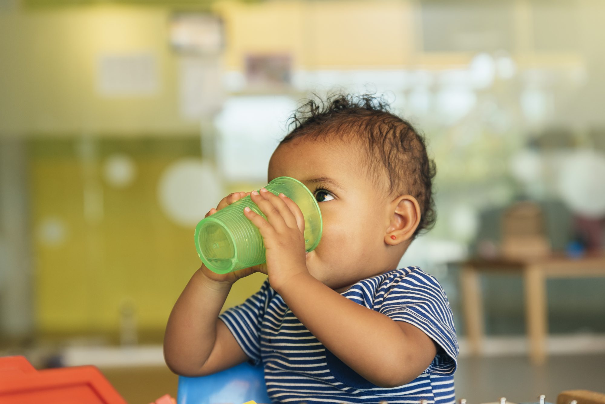 baby boy drinking water from a green cup