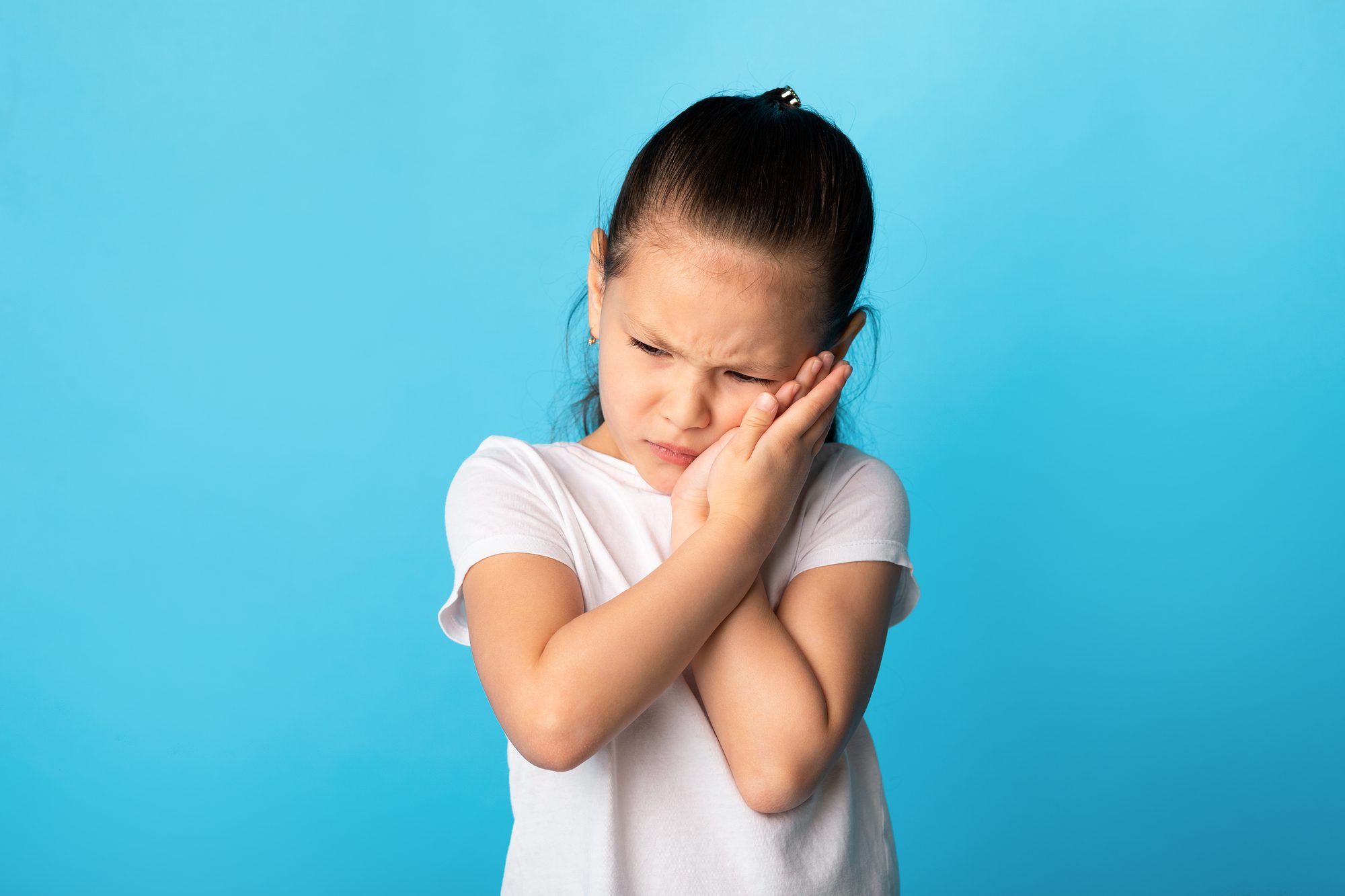Unhappy girl suffering from toothache from cavity, touching cheek