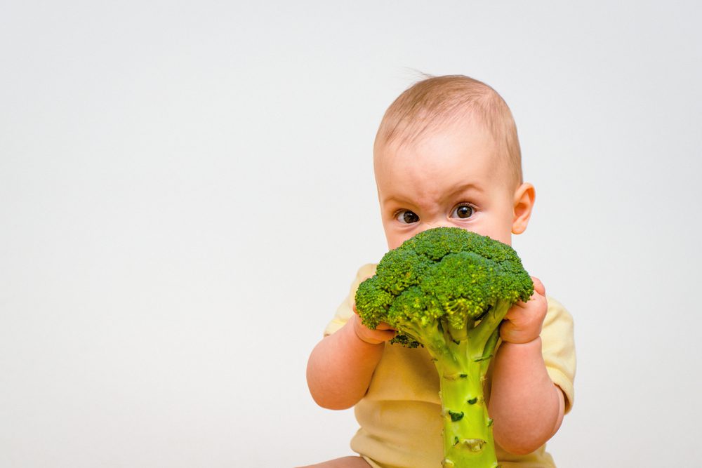 baby eating broccoli which is good for oral health for St. Patrick's Day