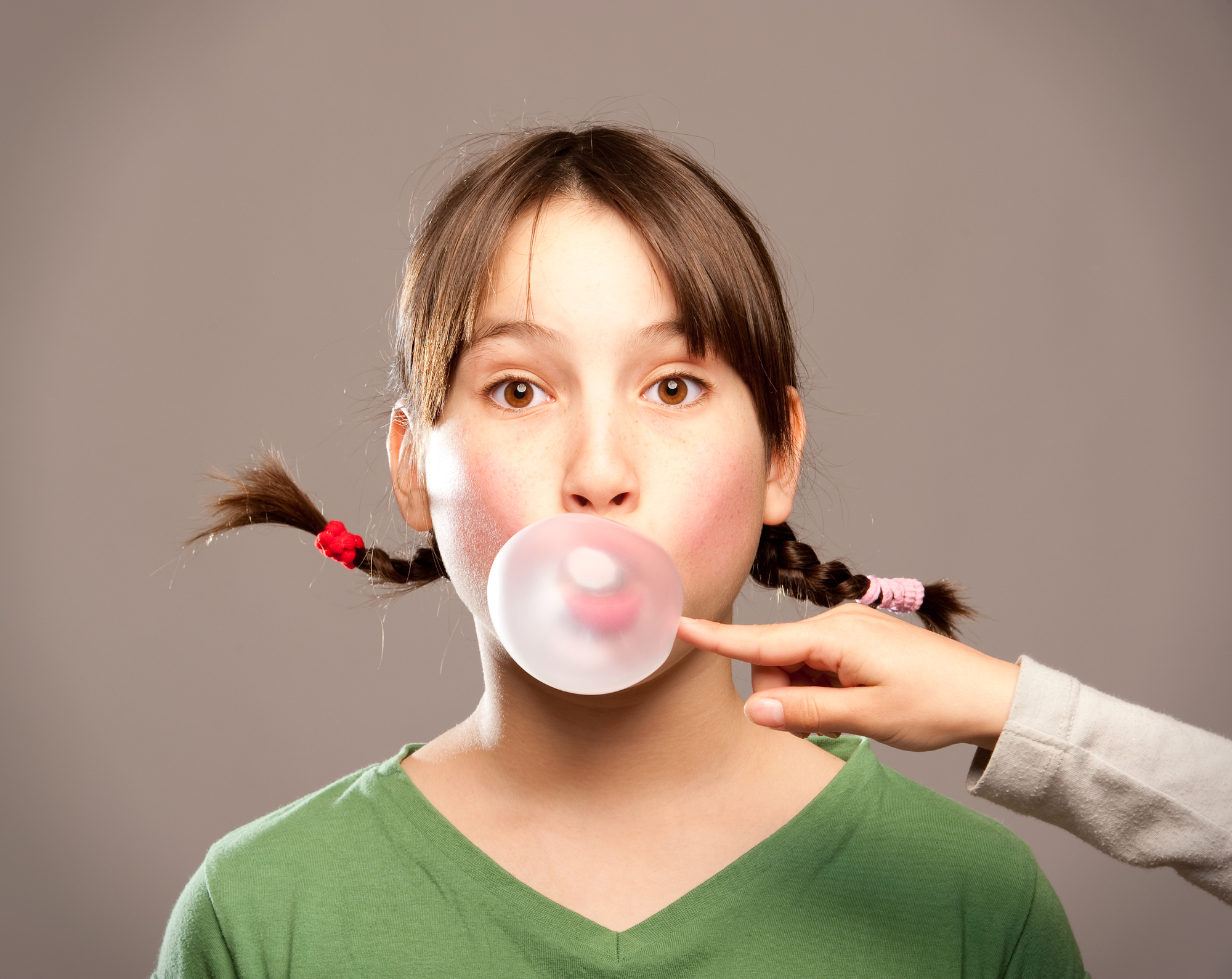 young girl making a bubble from chewing gum