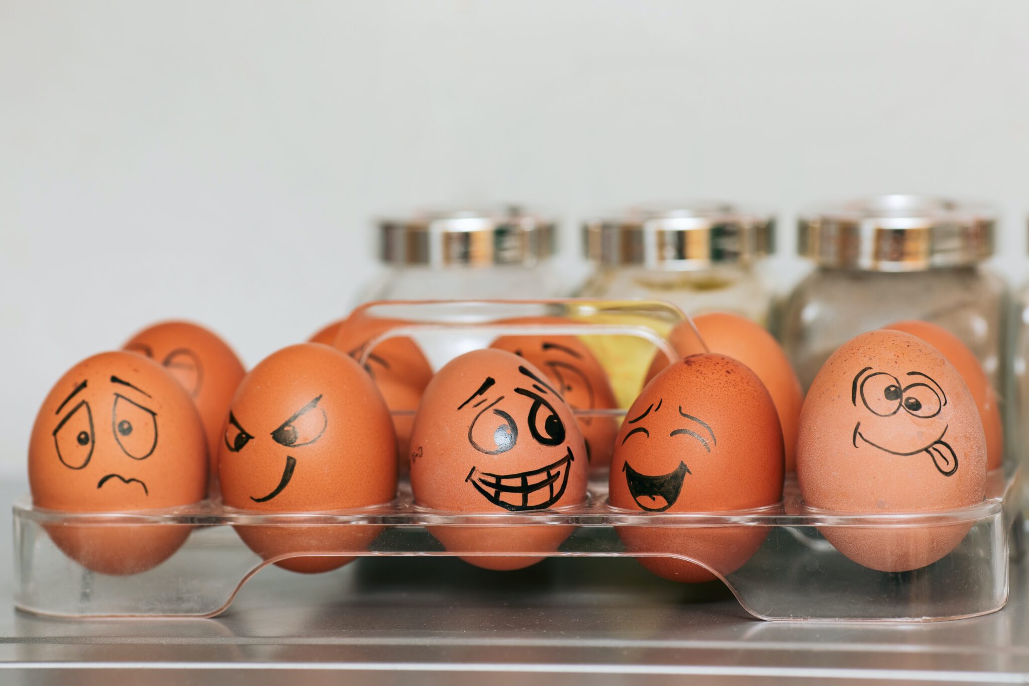 carton of brown eggs with funny faces drawn on