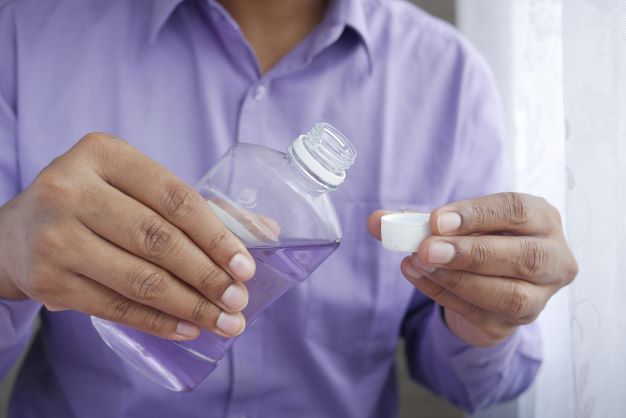 parent pours mouthwash into a cap