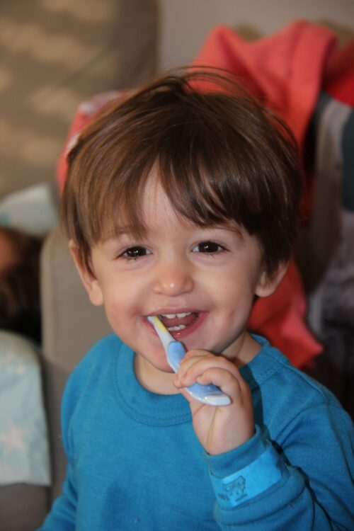 toddler brushing his teeth with a toothbrush