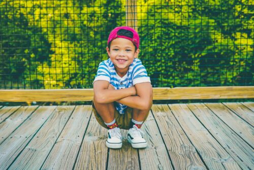 young boy sitting on a bridge smiling with his baby teeth showing