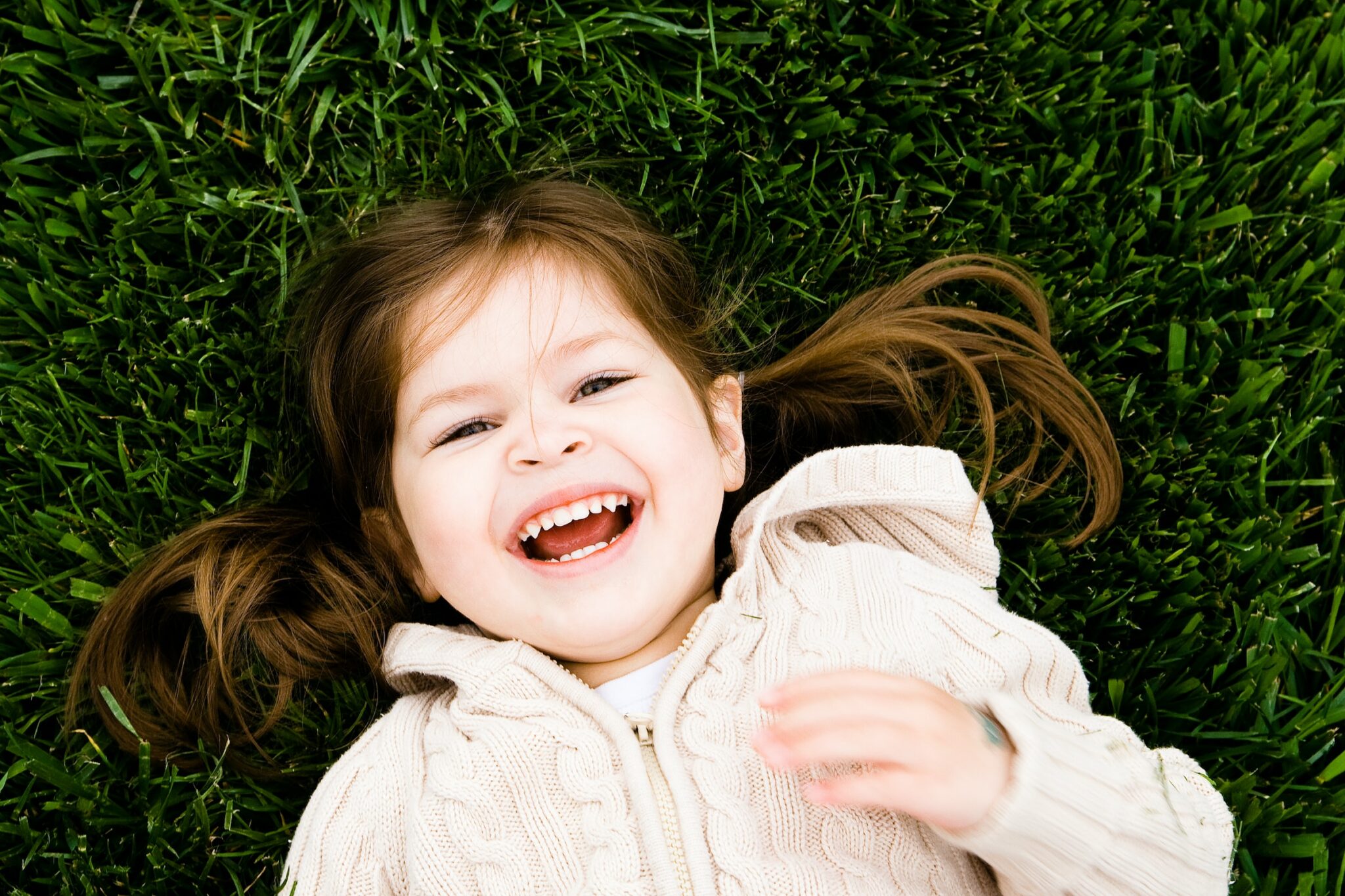 Little girl lying on the grass and smiling