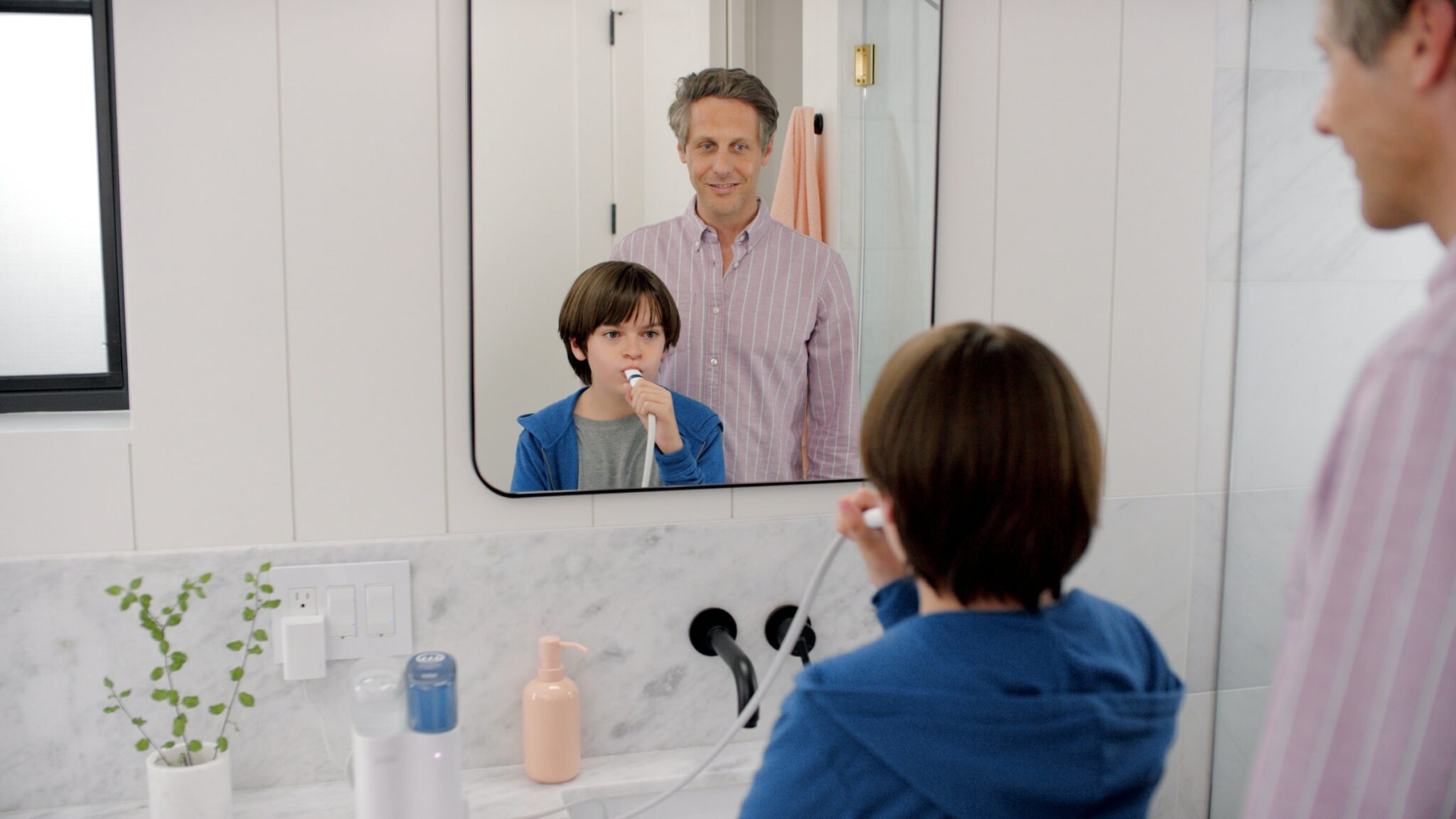 father and son in the bathroom while son is brushing teeth