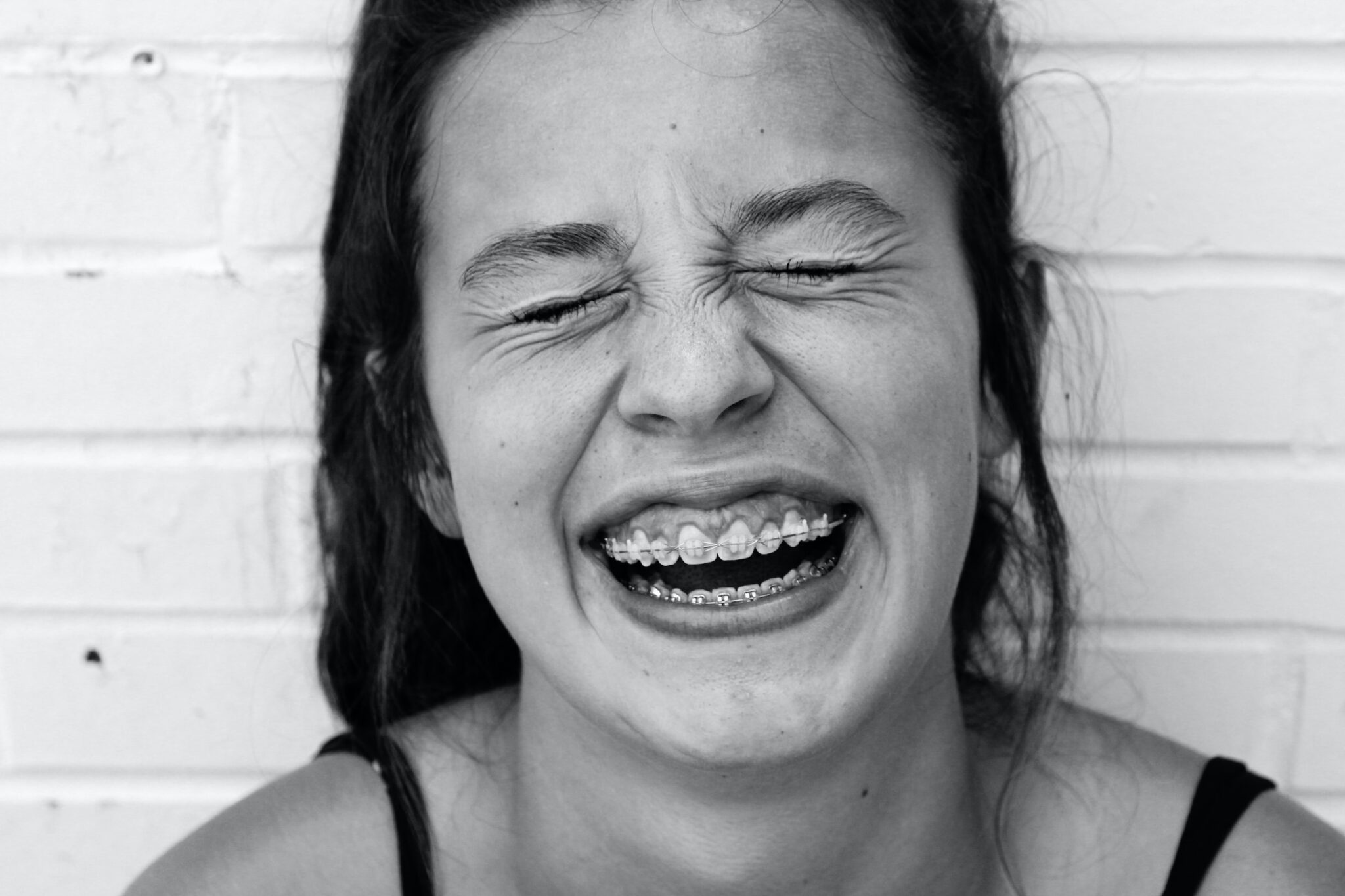 black and white photo of young girl with braces laughing