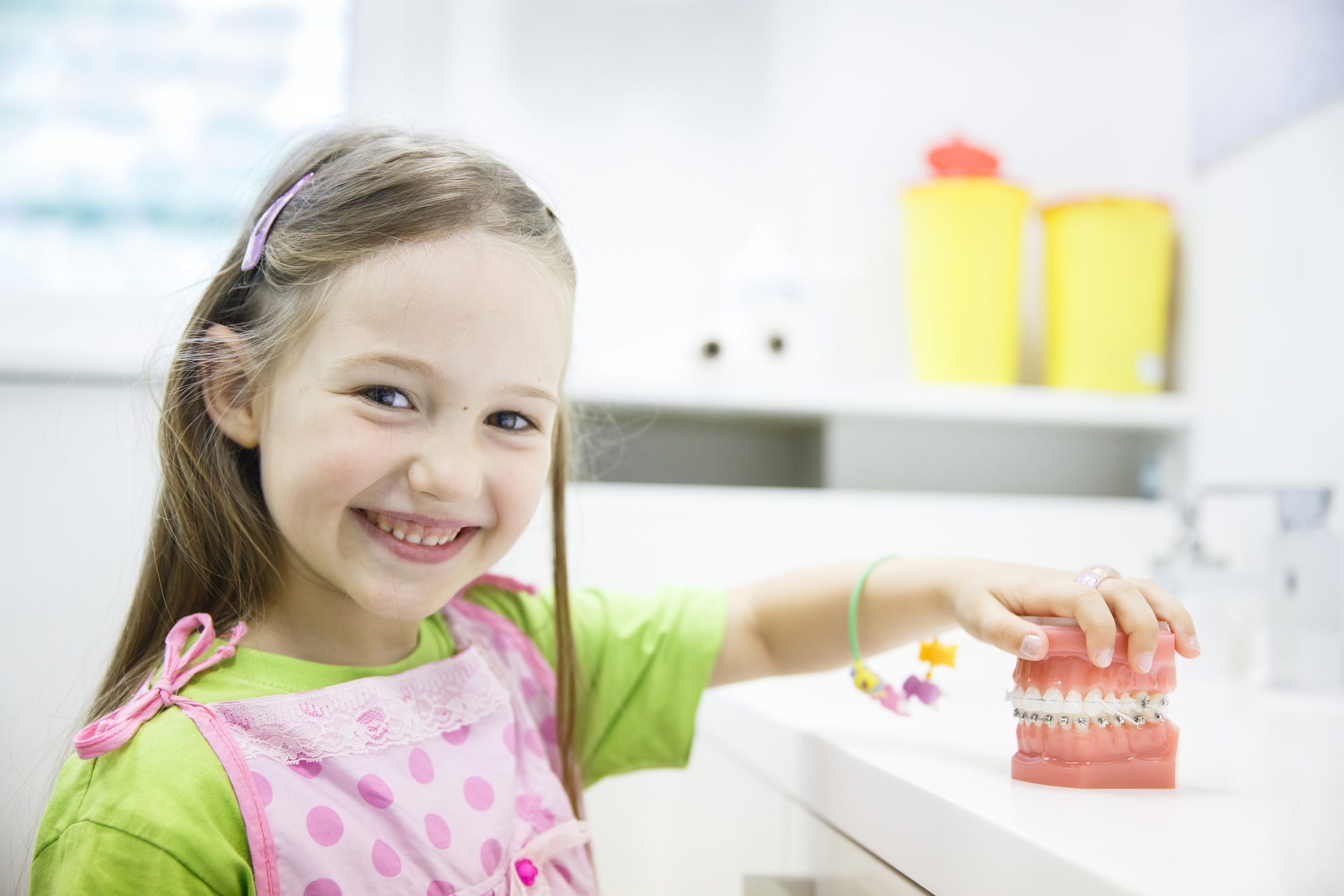 little girl at the dentist's office playing with prosthetic teeth