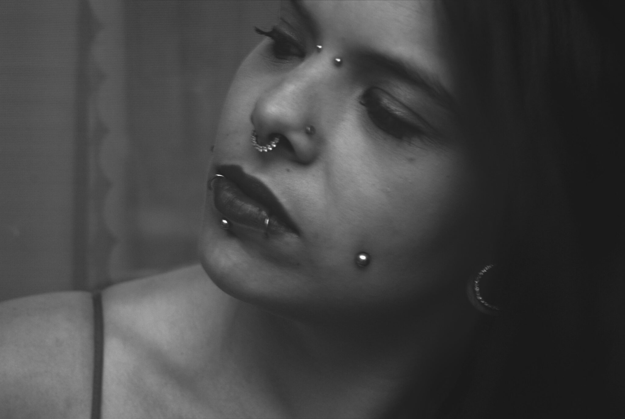 black and white picture of young girl with face and oral piercings